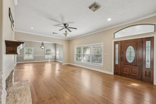 entryway with ceiling fan, hardwood / wood-style flooring, crown molding, and a high end fireplace