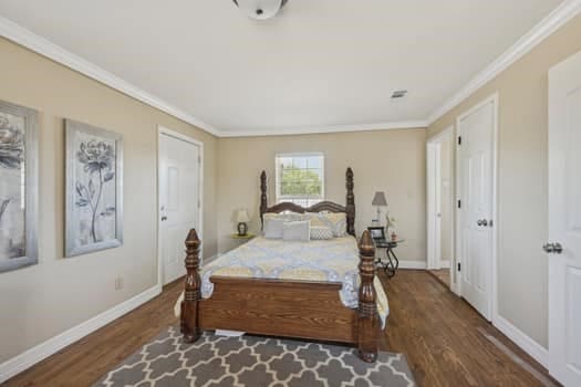 bedroom featuring crown molding and dark hardwood / wood-style flooring