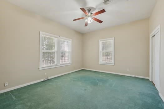 unfurnished room featuring ceiling fan and dark carpet