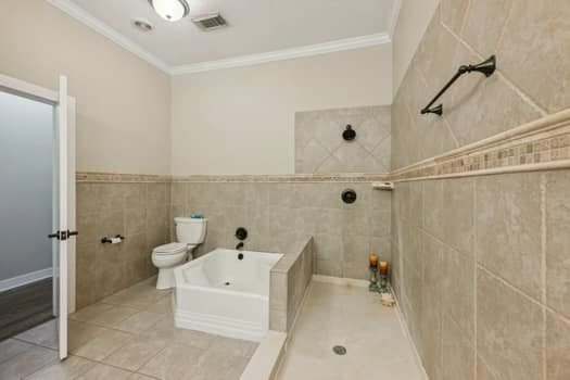 bathroom featuring separate shower and tub, tile patterned floors, tile walls, crown molding, and toilet