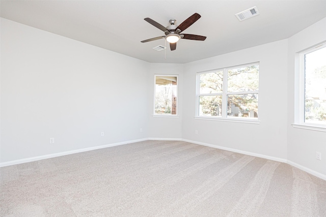 carpeted spare room featuring a wealth of natural light and ceiling fan