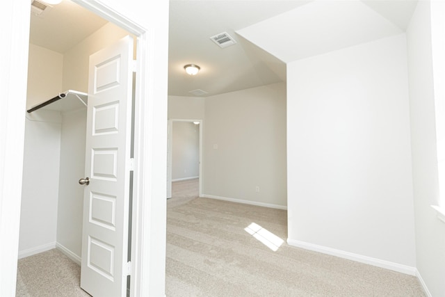 walk in closet with light carpet