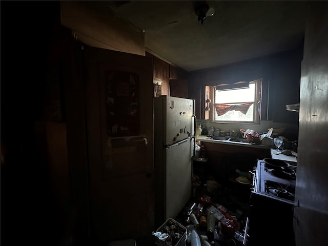 kitchen featuring black gas stove, sink, and white refrigerator