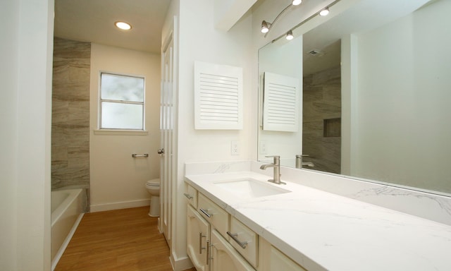 full bathroom with tiled shower / bath, hardwood / wood-style flooring, vanity, and toilet