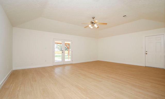 spare room featuring light hardwood / wood-style floors, a textured ceiling, lofted ceiling, ceiling fan, and french doors