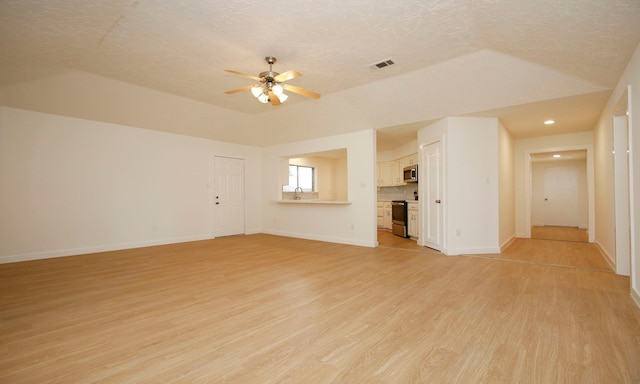 unfurnished living room featuring a textured ceiling, light hardwood / wood-style floors, lofted ceiling, and ceiling fan