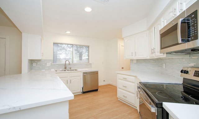 kitchen featuring light wood-type flooring, tasteful backsplash, sink, white cabinetry, and stainless steel appliances