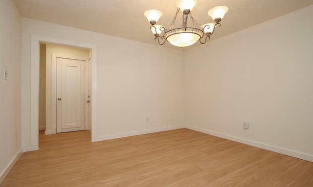 empty room with an inviting chandelier and light hardwood / wood-style floors