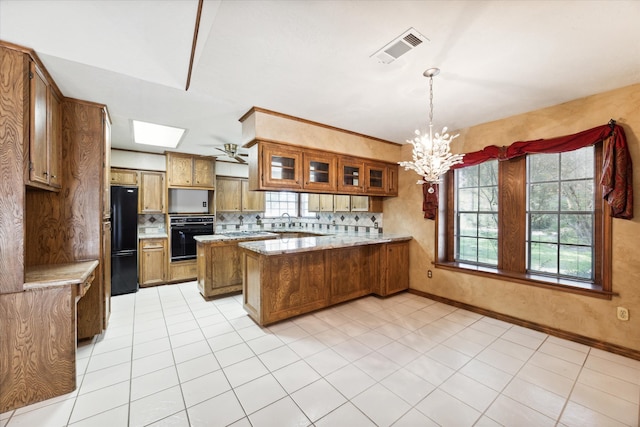 kitchen with light tile patterned floors, kitchen peninsula, decorative light fixtures, black appliances, and decorative backsplash