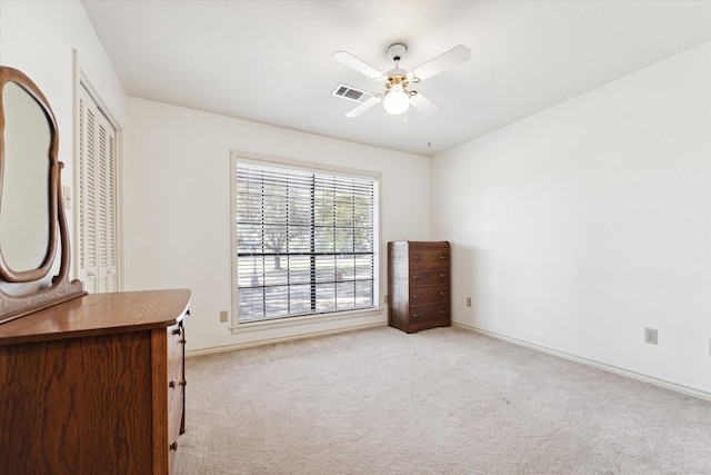 unfurnished bedroom featuring light carpet, a closet, and ceiling fan