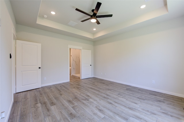 unfurnished room with ceiling fan, a raised ceiling, and light hardwood / wood-style floors