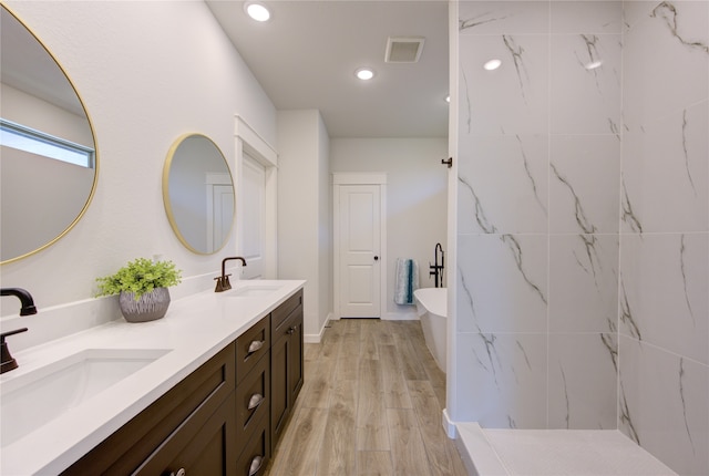 bathroom featuring hardwood / wood-style floors, a bath, and vanity