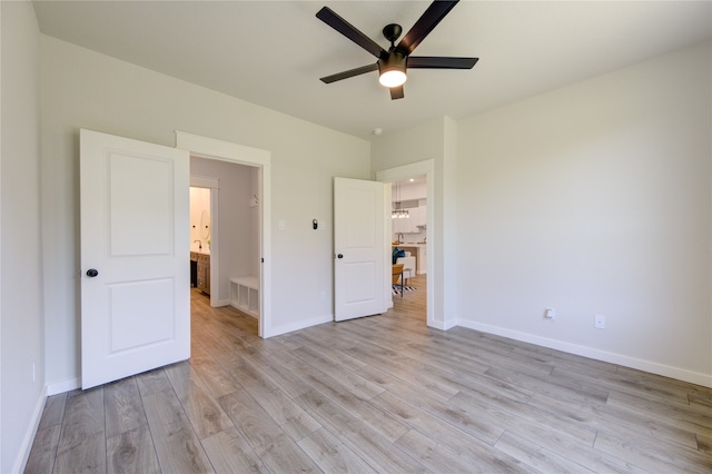 unfurnished bedroom with ceiling fan, light wood-type flooring, and ensuite bath