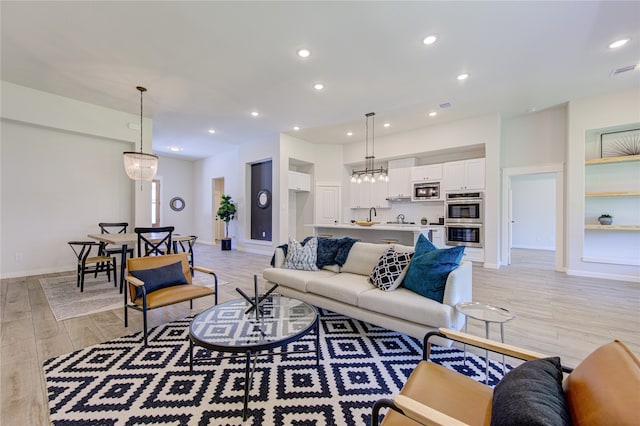 living room with light wood-type flooring and a chandelier