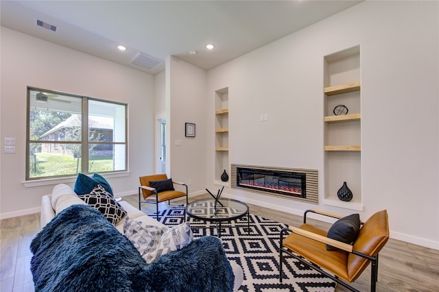 living room with built in shelves and hardwood / wood-style floors