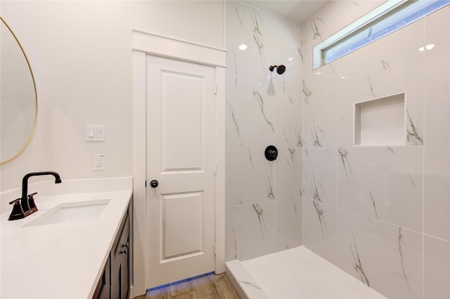 bathroom featuring a tile shower, vanity, and hardwood / wood-style floors