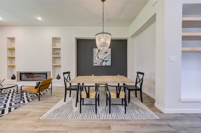 dining room with an inviting chandelier, built in features, and hardwood / wood-style floors