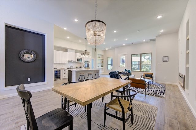 dining space featuring an inviting chandelier, light hardwood / wood-style flooring, and wine cooler