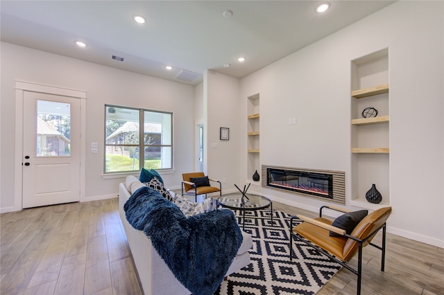 living room featuring light wood-type flooring and built in features