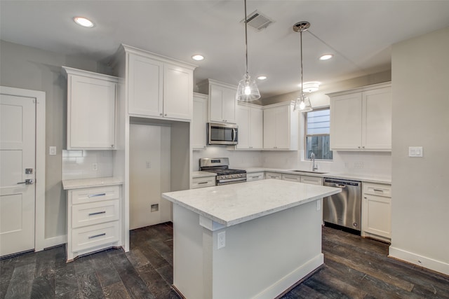 kitchen featuring appliances with stainless steel finishes, a kitchen island, dark hardwood / wood-style flooring, and white cabinets