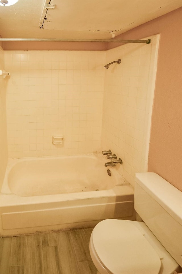 bathroom featuring wood-type flooring, toilet, and tiled shower / bath