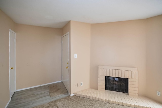 unfurnished living room with wood-type flooring and a brick fireplace