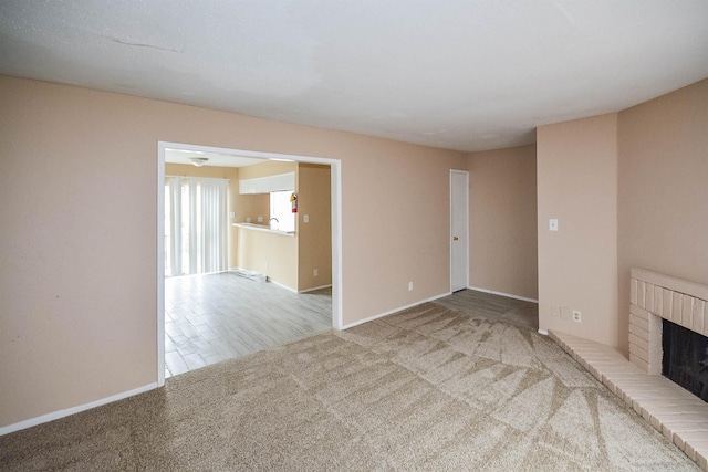 unfurnished living room featuring a brick fireplace and carpet