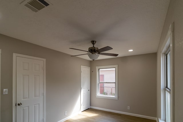 unfurnished room featuring a textured ceiling, light hardwood / wood-style floors, and ceiling fan