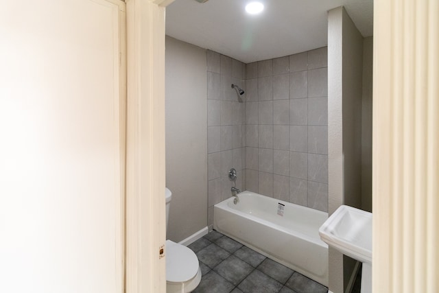 bathroom featuring tile patterned flooring, tiled shower / bath combo, and toilet