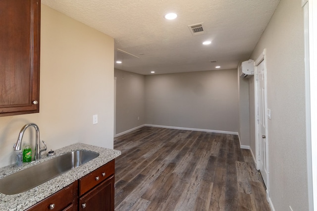 interior space featuring light stone counters, a textured ceiling, dark wood-type flooring, and sink