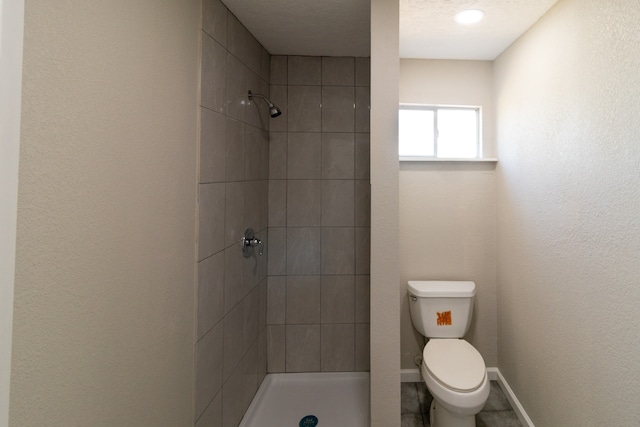 bathroom with a tile shower, a textured ceiling, and toilet