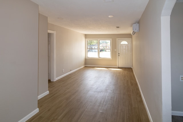 unfurnished room featuring wood-type flooring and a wall unit AC