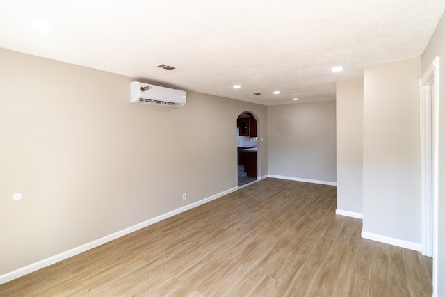 empty room with light hardwood / wood-style floors and a wall mounted air conditioner