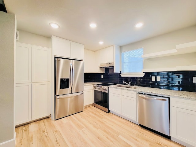 kitchen with light wood-type flooring, tasteful backsplash, white cabinets, stainless steel appliances, and light stone countertops