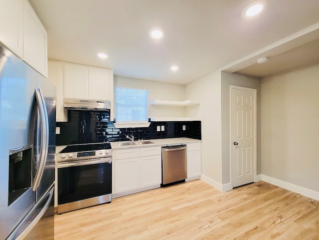 kitchen with appliances with stainless steel finishes, light hardwood / wood-style floors, white cabinetry, sink, and extractor fan