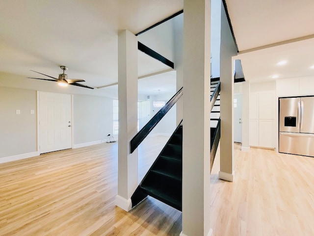 staircase with ceiling fan and hardwood / wood-style floors