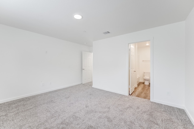 unfurnished bedroom with connected bathroom and light carpet