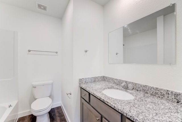 full bathroom featuring washtub / shower combination, hardwood / wood-style floors, vanity, and toilet