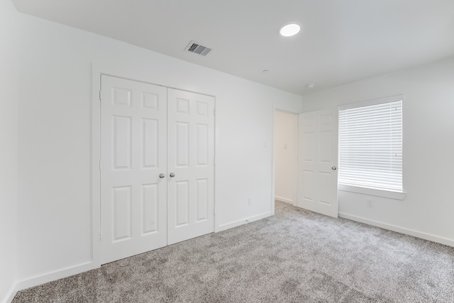 unfurnished bedroom featuring light colored carpet and a closet