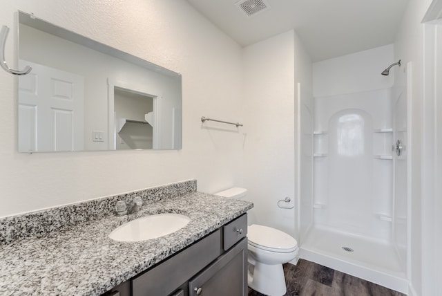 bathroom with vanity, a shower, hardwood / wood-style floors, and toilet