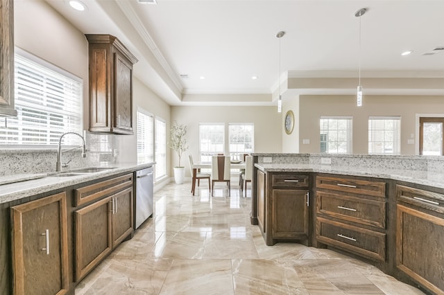 kitchen with light stone counters, sink, hanging light fixtures, ornamental molding, and stainless steel dishwasher