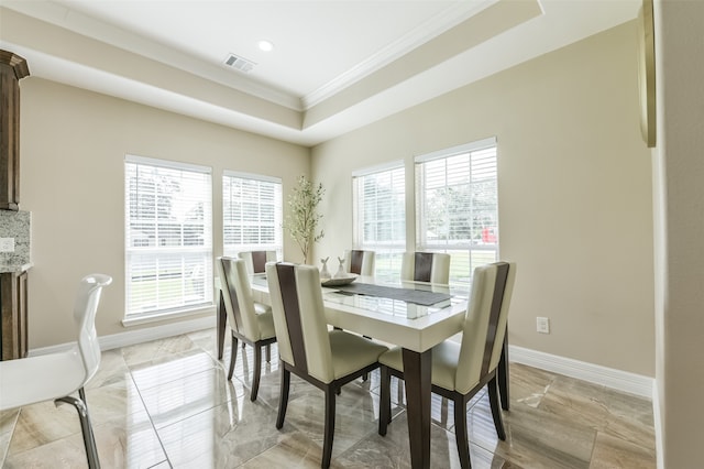 dining space with crown molding and a raised ceiling