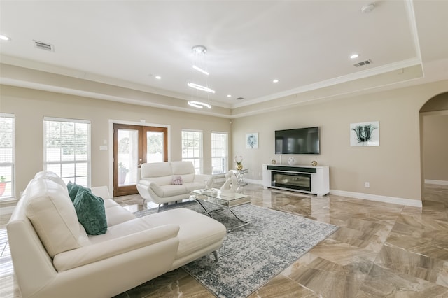 living room with ornamental molding, a raised ceiling, and french doors