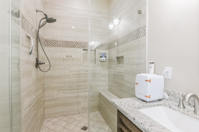 bathroom featuring tile patterned flooring, a shower with shower door, and vanity