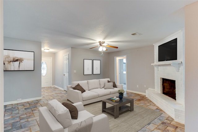 living room with a brick fireplace and ceiling fan