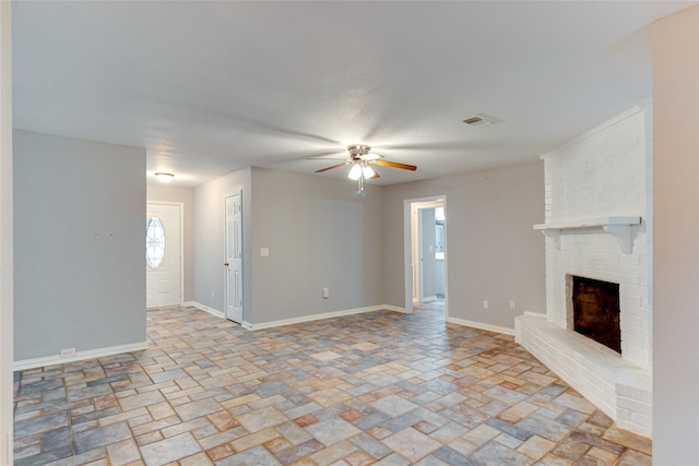 unfurnished living room with ceiling fan and a brick fireplace