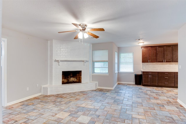 unfurnished living room with ceiling fan and a brick fireplace