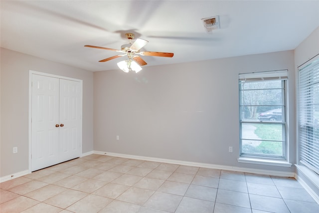 empty room with ceiling fan, light tile patterned flooring, and a healthy amount of sunlight