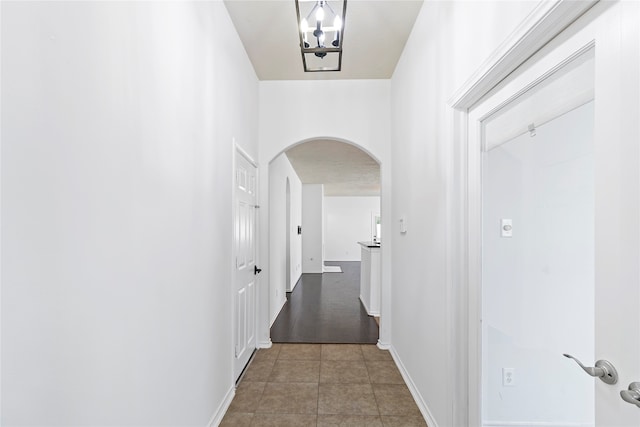 hall with an inviting chandelier and tile patterned flooring