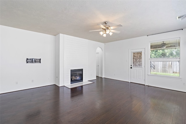 unfurnished living room with ceiling fan, dark hardwood / wood-style floors, and a large fireplace